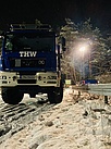 Einsatzfahrzeuge im Schnee mit Beleuchtungsmast im Hintergrund